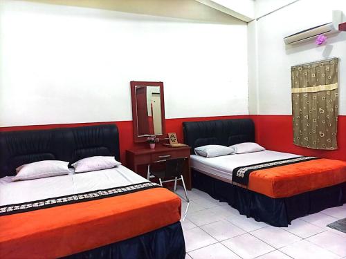 BangkinangHotel Al Madinah Bangkinang的配有镜子的客房内的两张床