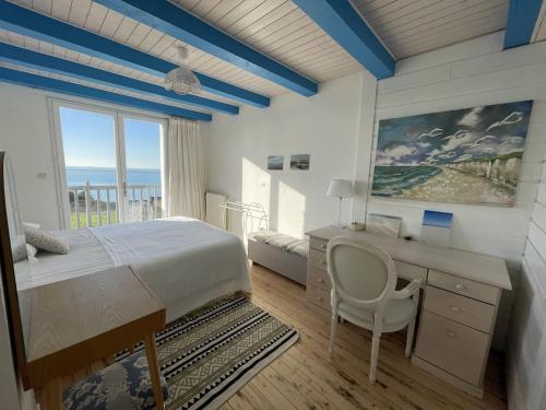 滨海布洛涅SERENITY VIEW Villa face mer aux magnifiques couchers de soleil的一间卧室配有一张床、一张书桌和一个窗户。