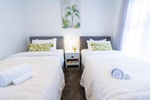 基督城Stylish 2-Bedroom Haven Next to Hagley Park的配有白色床单的客房内的两张单人床