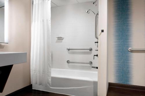 德梅因得梅因市中心万豪酒店的浴室配有淋浴帘和浴缸。