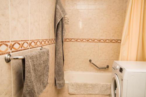 阿罗纳Best centric location for stay LA81的带浴缸和洗衣机的浴室。