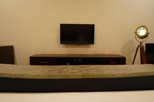 Pura RaghunāthHOTEL DHAROHAR的客厅配有电视和带床的桌子