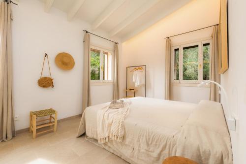 阿尔塔Es Pinaró Sansó的一间白色卧室,配有床和2个窗户