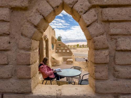 Naẖal Ya‘alonLotan Desert Travel Hotel的坐在石拱道桌子上的女人