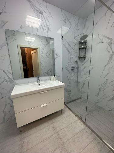 敖德萨Sky apartments Budova的浴室配有盥洗盆和带镜子的淋浴