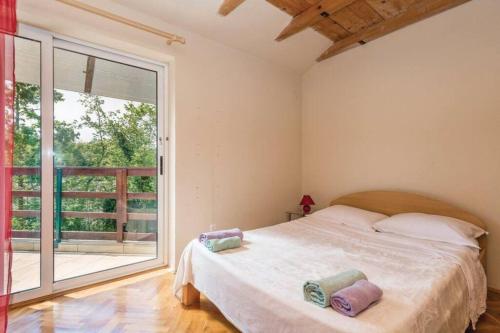 尤尔达尼Holiday home Brgud with private pool near Opatija的一间卧室设有一张床和一个大窗户