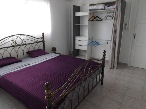 BaillifAux portes de la Soufrière, Baillif的一间卧室配有一张带紫色床单的床和一个衣柜