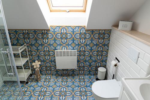 Borowy MłynRozmaryn - Komfortowy domek całoroczny na Kaszubach的浴室设有卫生间,铺有蓝色和白色瓷砖。