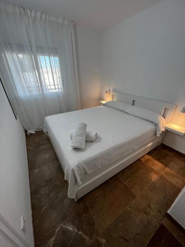 萨洛Apartamento a 3 minutos de la playa的窗户客房内的一张白色床