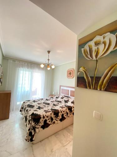 卡拉德费斯特拉特Apartamento Benidorm con piscina en la playa的卧室配有一张挂有花卉画的床铺。
