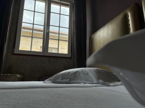 查韦斯Alojamento Central的卧室里带枕头的床,卧室里设有窗户