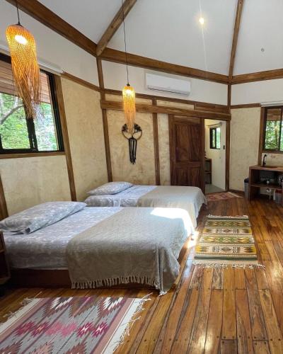 诺萨拉Casita Ylang Ylang的客房内设有两张床,铺有木地板,设有窗户。