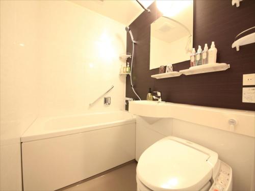 东京池袋百夫长酒店的白色的浴室设有卫生间和水槽。