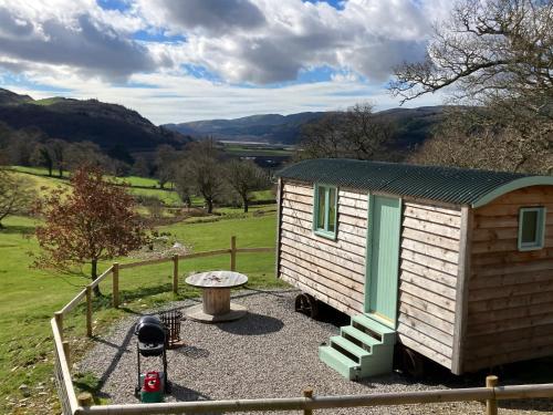 多尔盖罗Shepherds hut above mawddach estuary的小屋设有桌子和围栏