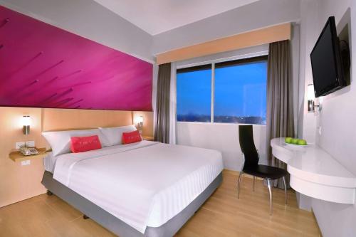 芝卡朗favehotel Jababeka Cikarang的酒店客房设有一张大床和一张书桌。
