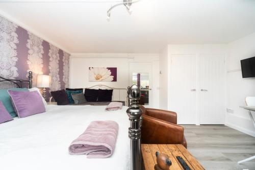 海维康11 Boutique studio apartment perfect for peaceful getaway, secluded garden, quiet location的卧室配有一张带紫色枕头的大型白色床。