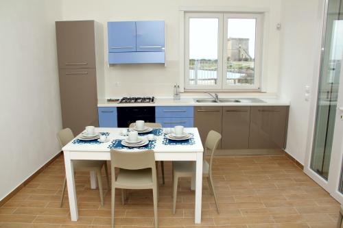 托雷拉皮罗Altomare Case Vacanza的厨房配有白色的桌椅和水槽