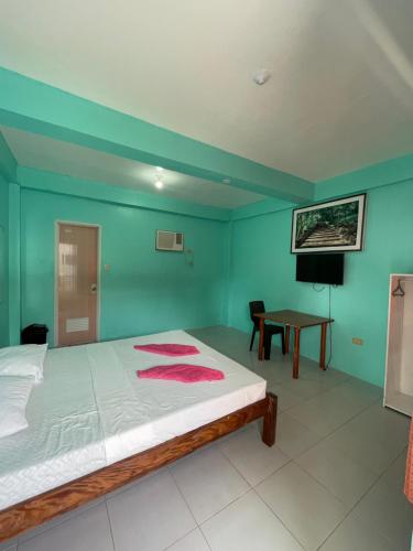 曼巴豪Medano Sunset Resort的一间卧室设有绿色的墙壁和一张带桌子的床