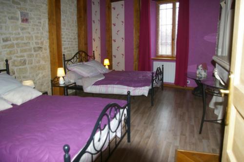 Laferté-sur-Aube金矿度假屋的配有紫色墙壁和木地板的客房内的两张床