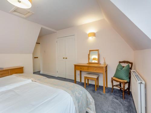 KiltarltyCruives Lodge的一间卧室配有一张床、一张桌子和一把椅子