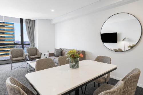 布里斯班Meriton Suites Herschel Street, Brisbane的一间设有白色桌子、椅子和镜子的客房