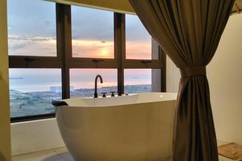马六甲NEW Cozy Seaview Bali Residences Studio 4pax near Jonker的带浴缸的浴室和窗户