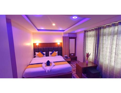 NamchiHotel Maurya Residency, Namchi的一间卧室配有一张特大号床和紫色灯
