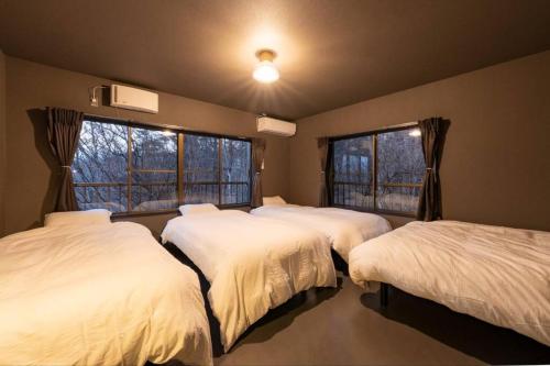 山中湖村tj resort YAMANAKAKO Luxury large villa with Mt. Fuji, Sauna BBQ Max 25的带三张床和两扇窗户的房间
