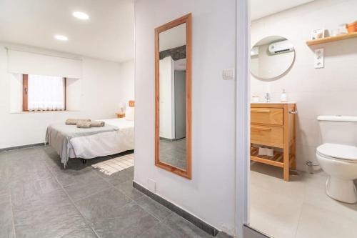 卡马乔Precioso piso estilo rústico a 10 min de Santander的浴室设有床、水槽和镜子