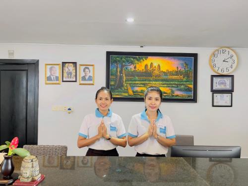 西哈努克玛丽海滩度假酒店的两个女孩站在一个房间里,手在祈祷