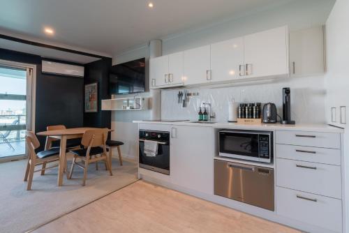 奥克兰Luxury Apartment - Parking - Hot Tub - Stunning Views的厨房配有白色橱柜和桌椅