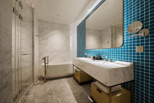 青岛青岛东方影都创智君亭酒店的浴室配有盥洗盆、镜子和浴缸