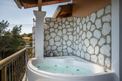 达西亚Aloe Seaview Apartments by Konnect, 500m from Dassia Beach的阳台设有浴缸,拥有石墙