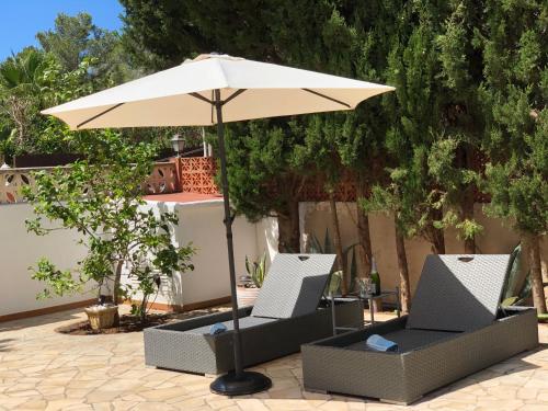 圣埃乌拉利亚Villa Casa Diego Ibiza的一把伞和桌子下的两把椅子