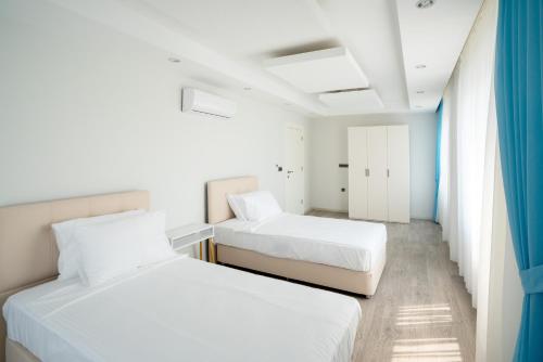 安塔利亚River Park Residence Lara的配有2张床的白色墙壁和蓝色窗帘