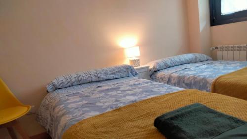 柯米拉斯El Mirador del Valle, a 9 min de Comillas的一间卧室设有两张床,墙上配有一盏灯。