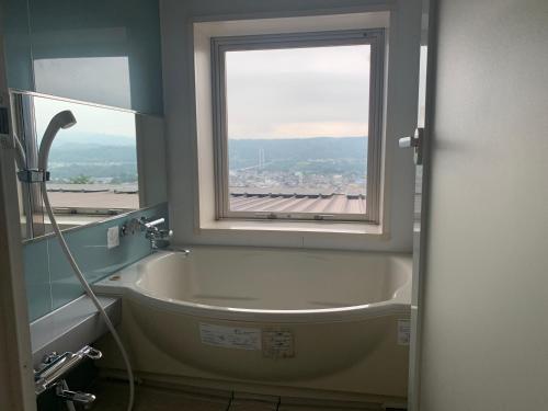 秩父市天然农场城市诺恩日式旅馆的带浴缸的浴室和窗户