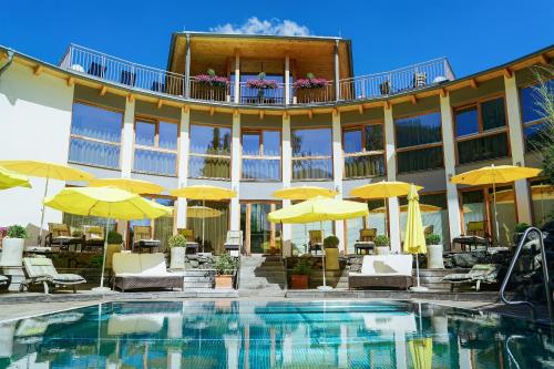 巴德小基希海姆奥特内斯埃斯岑霍夫 - 阿尔卑斯斯罗尼斯酒店的一座设有游泳池和黄色遮阳伞的酒店