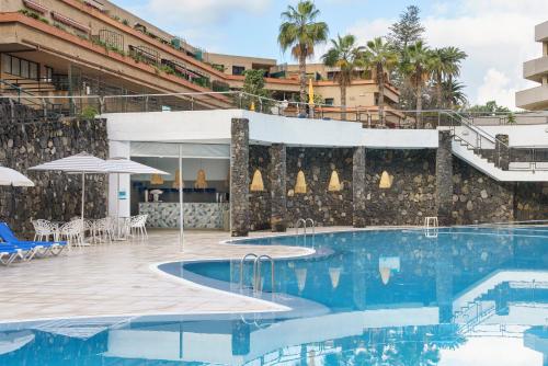 拉克鲁斯Alua Tenerife的一个带桌子和遮阳伞的酒店游泳池