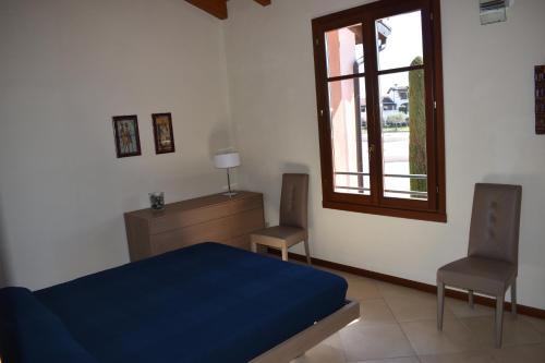 佩斯基耶拉德加达Esclusivo trilocale con piscina al Garda Resort Village的一间卧室配有蓝色的床和两把椅子