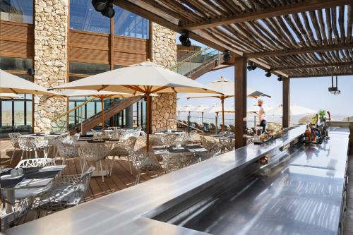 米茨佩·拉蒙Beresheet by Isrotel Exclusive的酒吧配有桌椅和遮阳伞