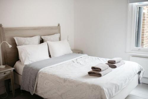 里士满3 Bedroom House in Kew Gardens的白色卧室,配有带毛巾的床