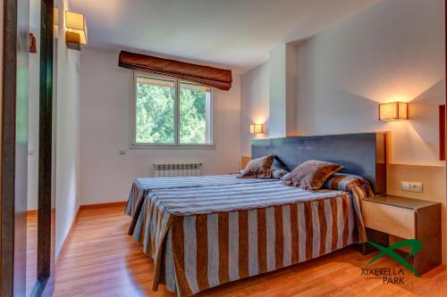 希塞雷拉Apartamentos Xixerella Park Resort的一间卧室配有一张带蓝色床头板的床和窗户