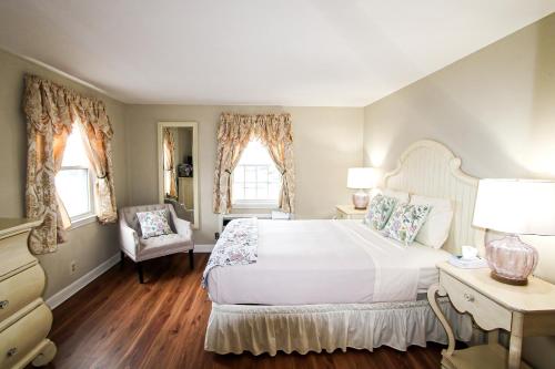 锡康克Colonial Inn Seekonk的卧室配有一张白色大床和一把椅子