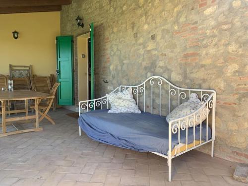 萨韦纳河畔圣拉扎罗Casale IL SAMBUCO sui colli bolognesi的一张金属床,坐在带桌子的庭院
