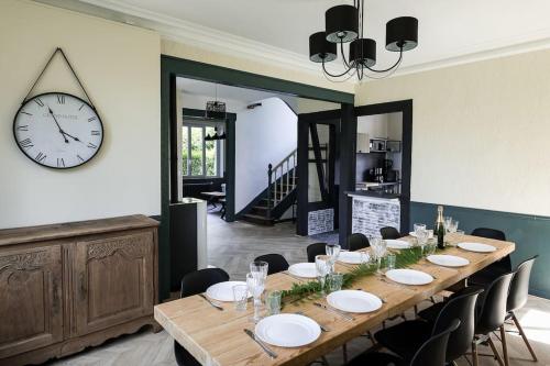 弗尔黎祖La Villa de l'Etoile 10 personnes的一间设有桌子和墙上时钟的餐厅