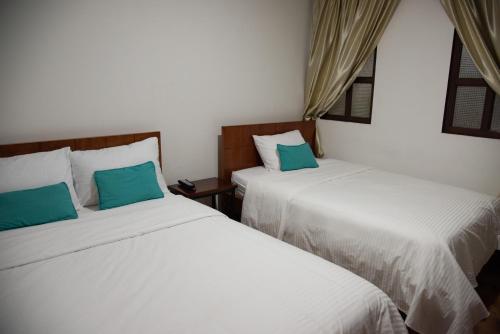波帕扬Hotel Lili - Popayán的两张睡床彼此相邻,位于一个房间里