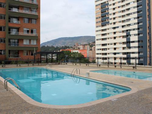 麦德林Apartamento Completo Poblado - Ubicacion Central con Parqueadero的一座大型游泳池,位于部分建筑前