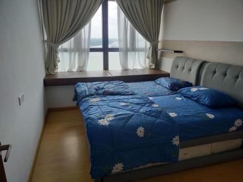 新山Royal Strand Danga Bay Abang Payung的一间卧室配有一张带蓝色棉被的床和窗户。