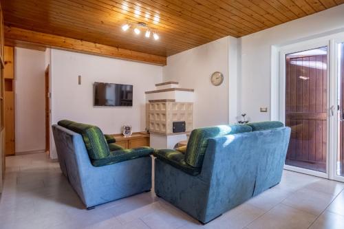 普雷达佐DolomiApartments - Casa Lagorai的客厅设有两把蓝色椅子,配有电视